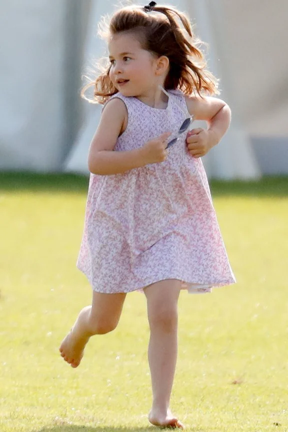 Princess Charlotte running on a feild in a dress.
