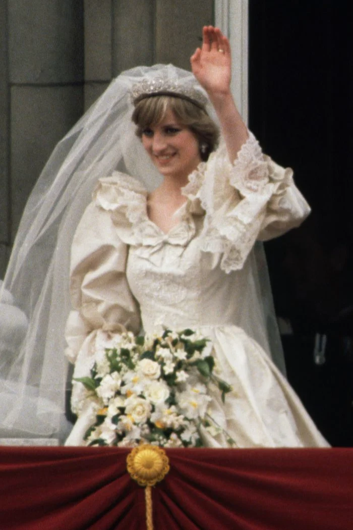 Princess Diana on her wedding day waving while holding her bouquet.